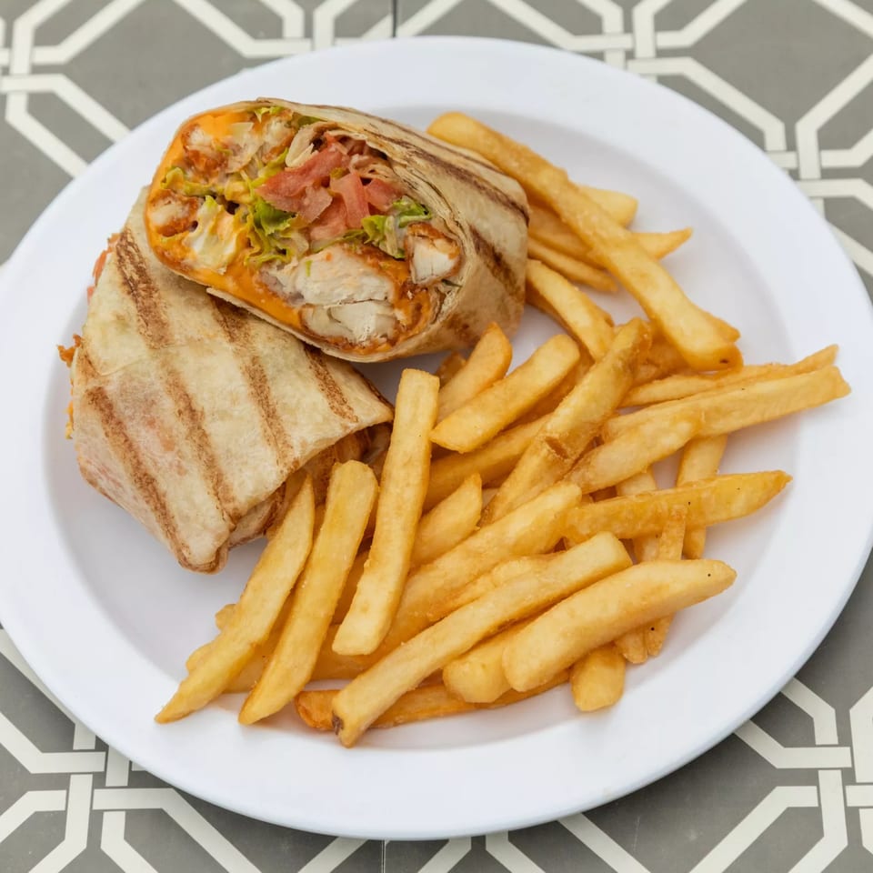 Grilled chicken wrap with lettuce, tomato, and cheese, served with a side of golden french fries.