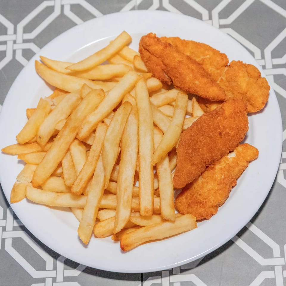 A white plate filled with golden french fries and several crispy chicken tenders on a patterned table.