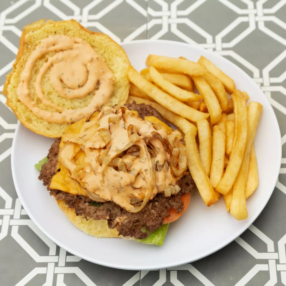 Island Social's burger with melted cheese, caramelized onions, special sauce, and a side of fries.